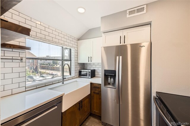 303 W Lehow Ave Unit 22, Englewood, CO 80110 - kitchen featuring appliances with stainless steel finishes, lofted ceiling, tasteful backsplash, light countertops, and white cabinets