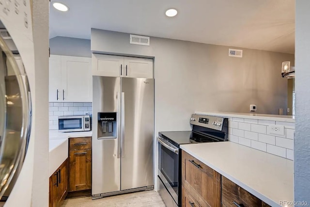 303 W Lehow Ave Unit 22, Englewood, CO 80110 - kitchen featuring stainless steel appliances, decorative backsplash, light wood-type flooring, white cabinets, and recessed lighting