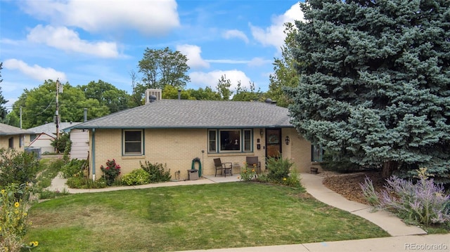 single story home with roof with shingles, a front lawn, a patio, and brick siding