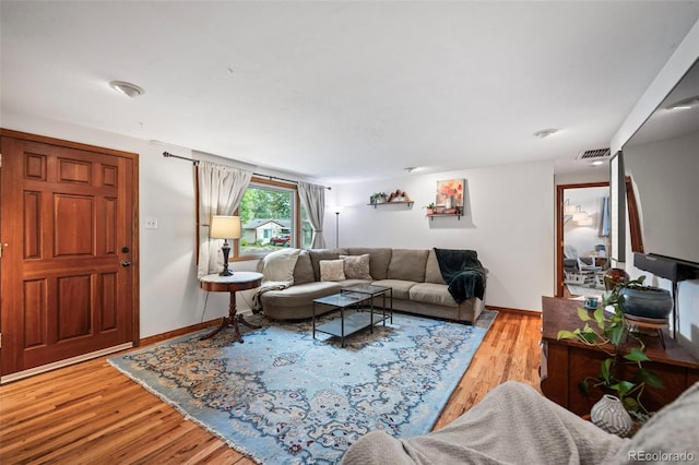 living area featuring baseboards, visible vents, and wood finished floors