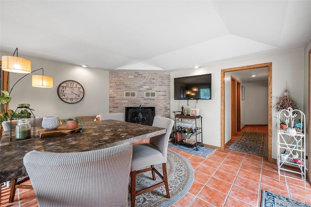 kitchen featuring lofted ceiling, light tile patterned flooring, a fireplace, and baseboards