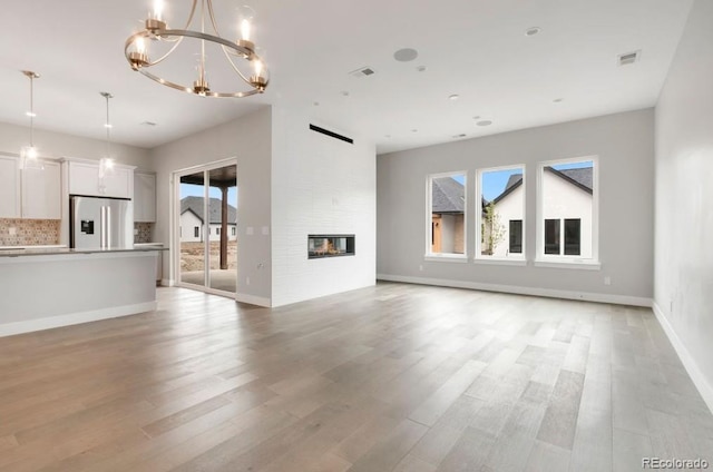 1744 Barefoot Dr, Windsor, CO 80550 - unfurnished living room with plenty of natural light, a chandelier, light wood-style floors, and a fireplace