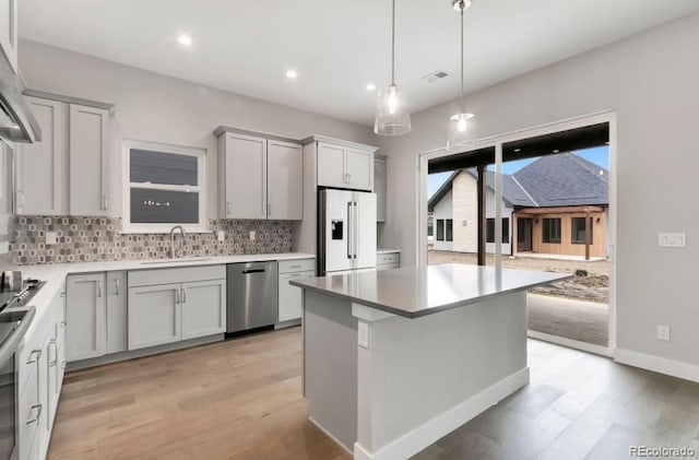 1744 Barefoot Dr, Windsor, CO 80550 - kitchen featuring tasteful backsplash, light wood finished floors, stainless steel dishwasher, white fridge with ice dispenser, and a center island