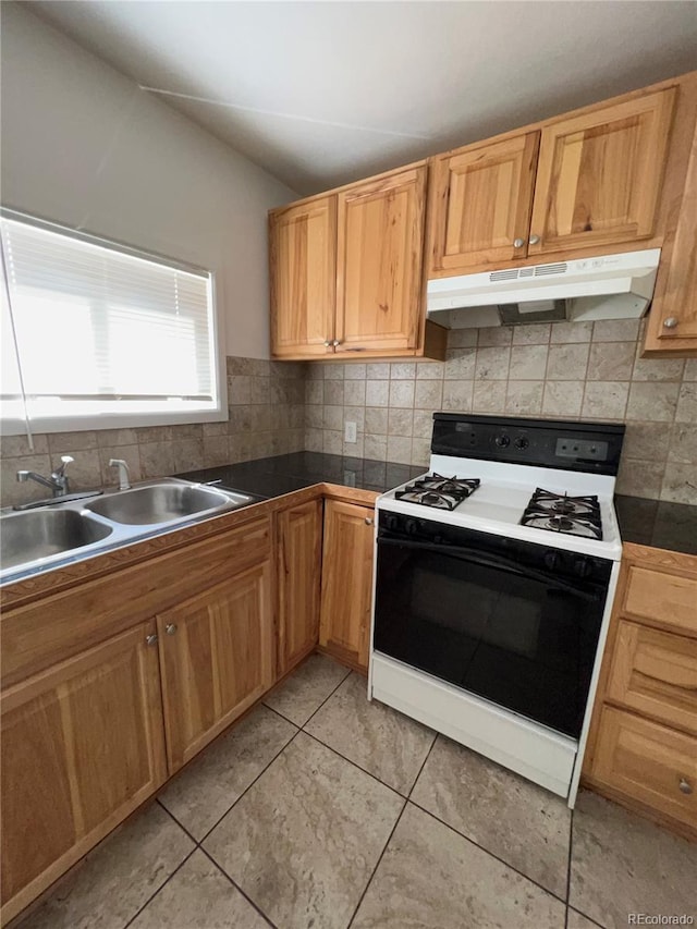 kitchen featuring light tile patterned flooring, white stove, sink, and decorative backsplash