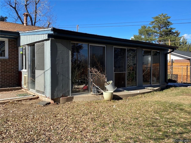 rear view of house featuring a yard and a sunroom