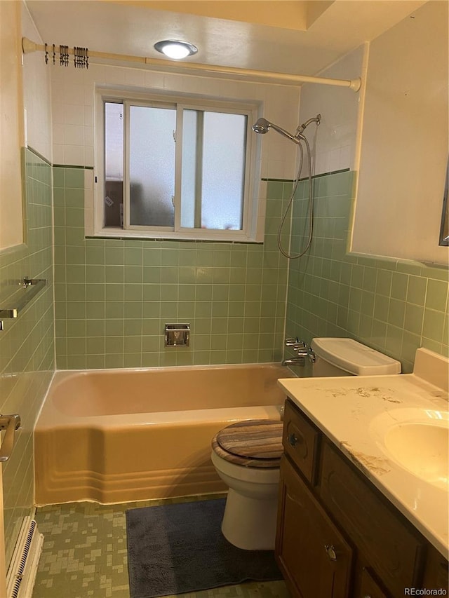 full bathroom featuring vanity, toilet, tiled shower / bath combo, and tile walls