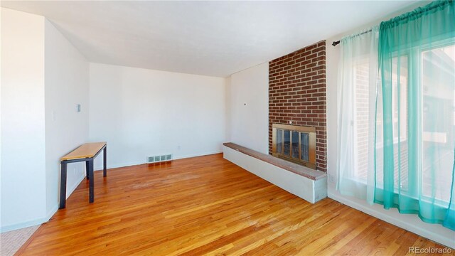 unfurnished living room featuring light wood-type flooring, a fireplace, and visible vents