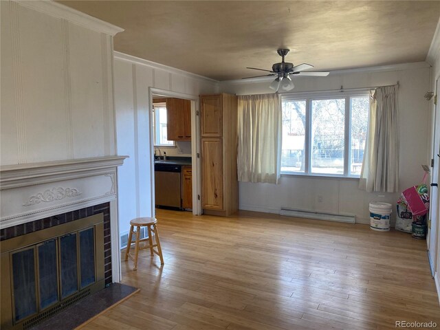 living room with ceiling fan, a baseboard heating unit, light wood-style floors, a tiled fireplace, and crown molding