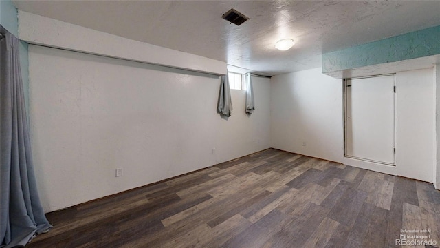 below grade area featuring a textured ceiling, wood finished floors, and visible vents