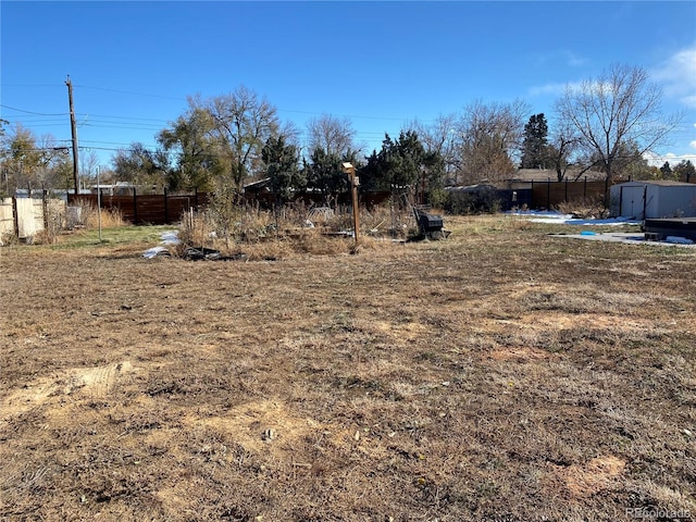 view of yard featuring an outbuilding, fence, and a shed