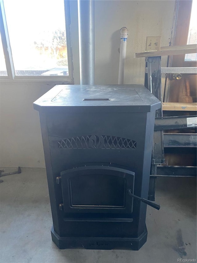 interior details with unfinished concrete flooring and a wood stove