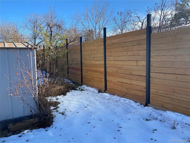 snowy yard featuring an outbuilding and fence