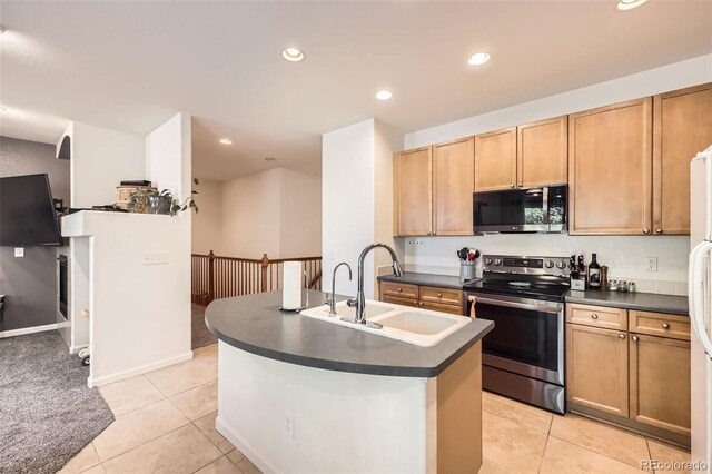12 Apache Plume St, Brighton, CO 80601 - kitchen with stainless steel appliances, dark countertops, light tile patterned floors, recessed lighting, and an island with sink
