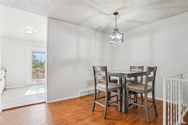 1733 S Nucla St, Aurora, CO 80017 - dining room with light wood-style flooring, a textured ceiling, and a chandelier