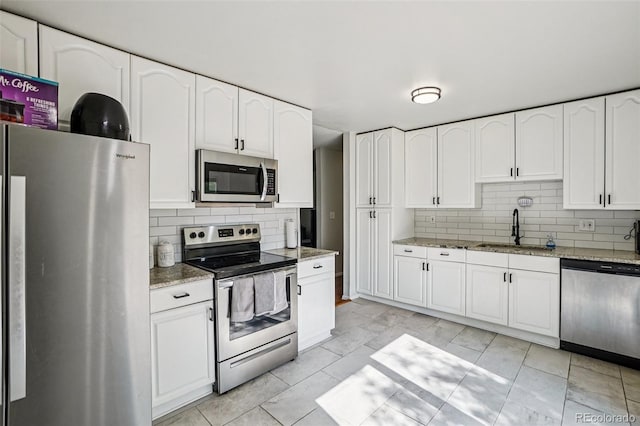 1733 S Nucla St, Aurora, CO 80017 - kitchen featuring stainless steel appliances, decorative backsplash, light stone counters, white cabinets, and light marble finish flooring