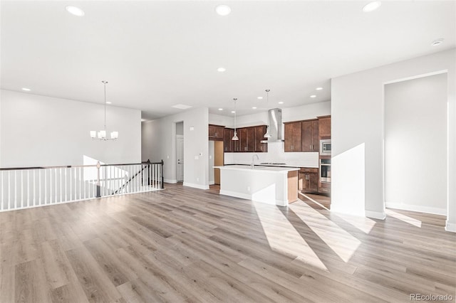 unfurnished living room with sink, an inviting chandelier, and light hardwood / wood-style floors