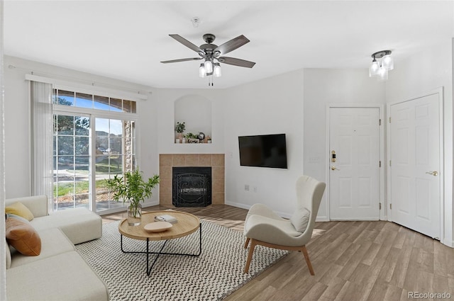 living room featuring ceiling fan, light hardwood / wood-style flooring, and a fireplace