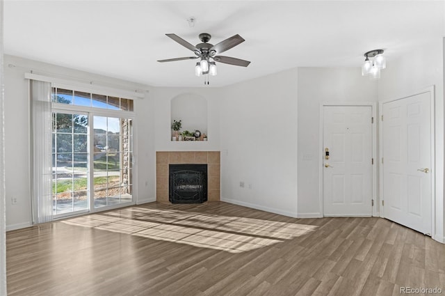 unfurnished living room with ceiling fan, light hardwood / wood-style flooring, and a tile fireplace