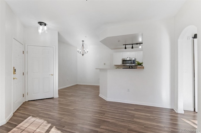 unfurnished living room with a notable chandelier and wood-type flooring