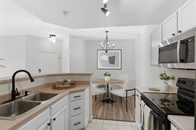 kitchen with a chandelier, black / electric stove, pendant lighting, white cabinets, and sink