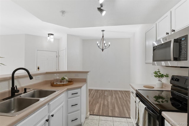 kitchen featuring sink, white cabinets, black electric range, hanging light fixtures, and a chandelier