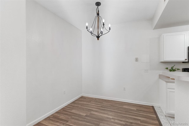 unfurnished dining area featuring hardwood / wood-style flooring and a chandelier