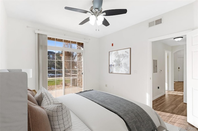 bedroom featuring ceiling fan, light hardwood / wood-style flooring, multiple windows, and electric panel