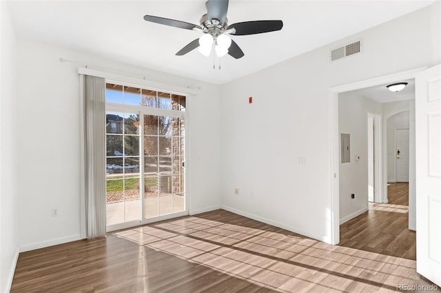 empty room with electric panel, ceiling fan, and hardwood / wood-style floors