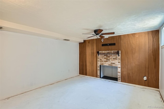 2692 S Osceola St, Denver, CO 80219 - unfurnished living room with ceiling fan, wooden walls, a fireplace, and concrete floors