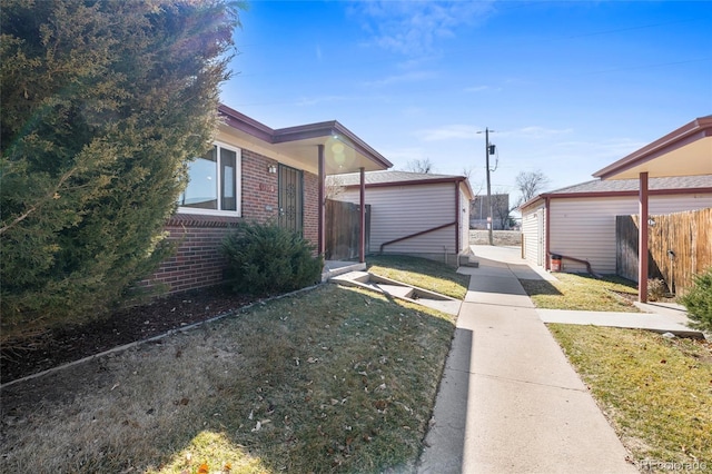 view of side of home with brick siding, a yard, and fence