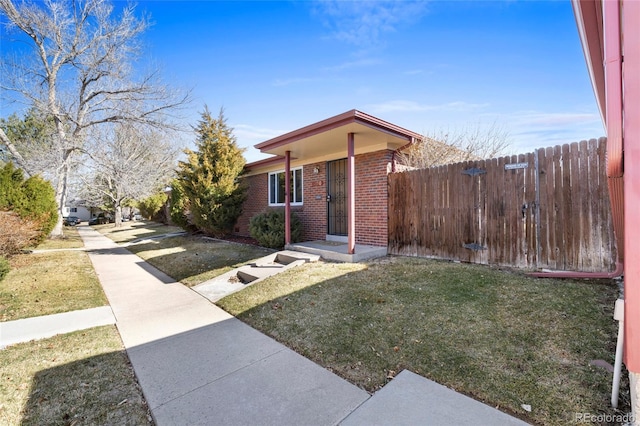 view of front of property featuring fence, a front lawn, and brick siding