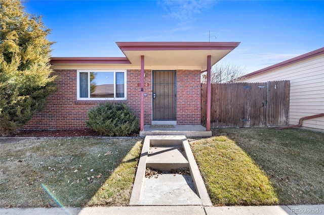 exterior space with fence, a front lawn, and brick siding