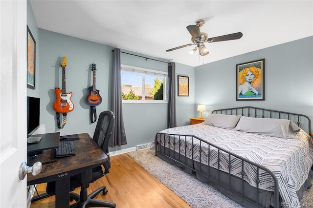 bedroom featuring a ceiling fan, visible vents, baseboards, and wood finished floors