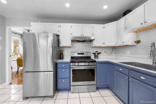 kitchen featuring light tile patterned floors, blue cabinetry, stainless steel appliances, under cabinet range hood, and a sink