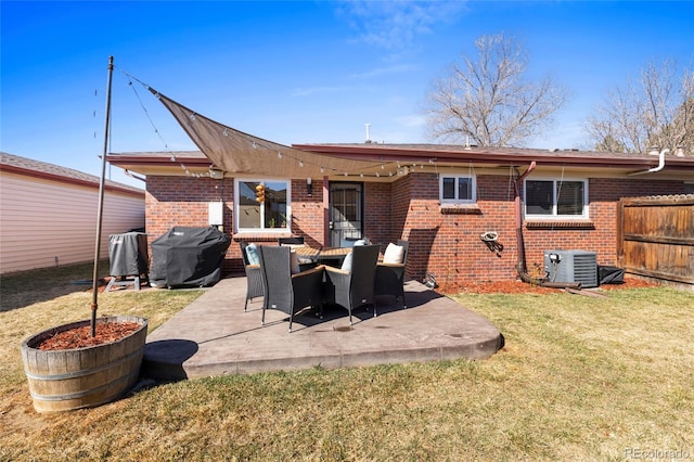 rear view of property featuring a patio, central AC, brick siding, fence, and a yard