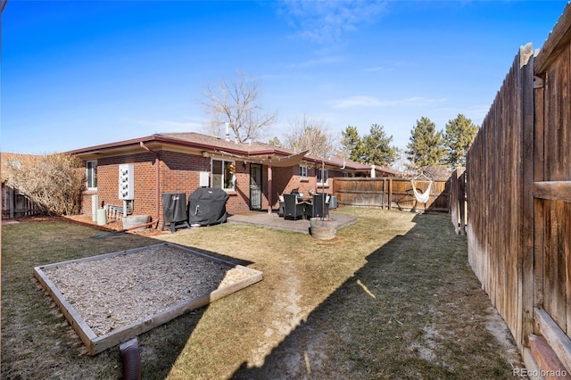 rear view of house featuring a yard, a fenced backyard, a patio, and brick siding