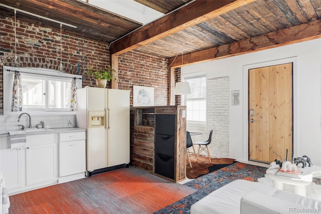 kitchen with brick wall, a sink, a healthy amount of sunlight, and white fridge with ice dispenser