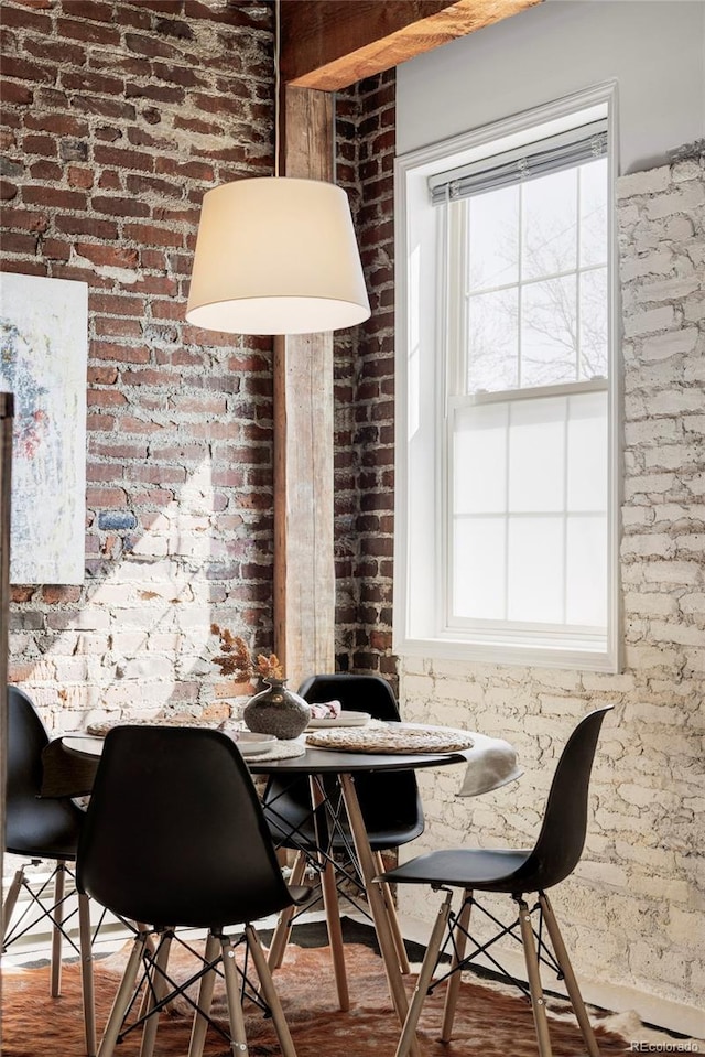 dining area with wood finished floors and brick wall