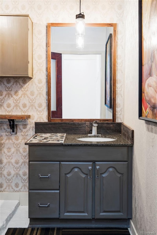 bathroom with vanity, baseboards, and wallpapered walls