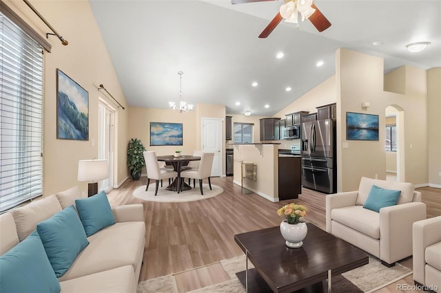 living room featuring arched walkways, high vaulted ceiling, ceiling fan with notable chandelier, recessed lighting, and light wood-type flooring