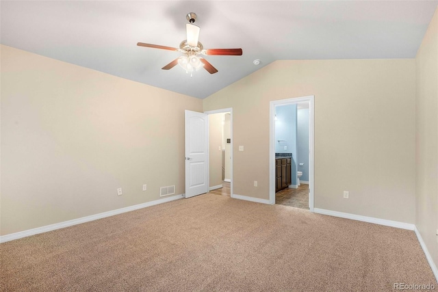 unfurnished bedroom with light colored carpet, visible vents, vaulted ceiling, baseboards, and connected bathroom