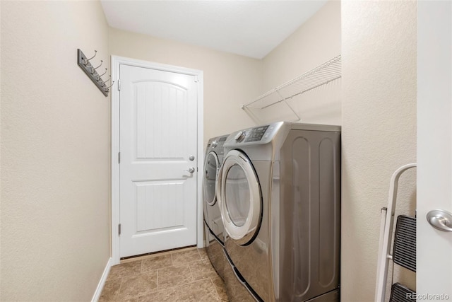 clothes washing area featuring baseboards, laundry area, and washing machine and clothes dryer