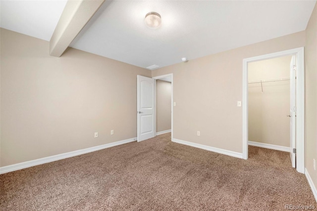 unfurnished bedroom with baseboards, a spacious closet, and carpet