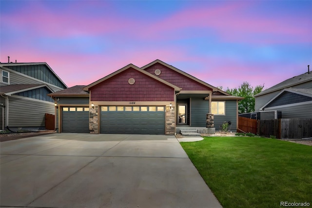 view of front facade featuring driveway, a front yard, a garage, fence, and stone siding