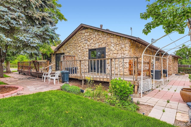 8644 S Brentwood St, Littleton, CO 80128 - back of house featuring stone siding, a patio area, a wooden deck, and a lawn