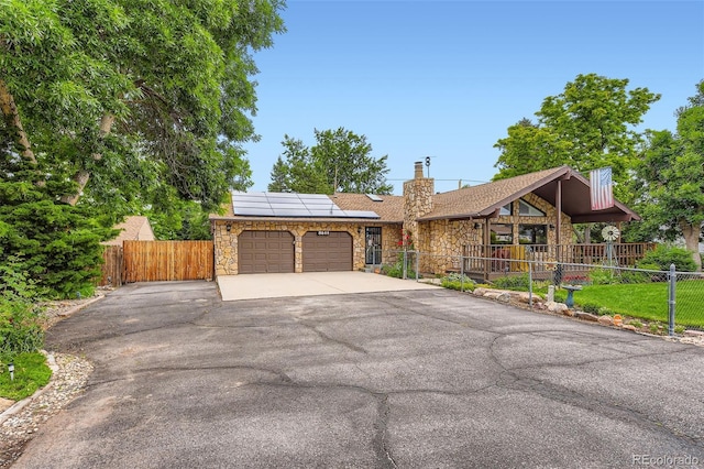 8644 S Brentwood St, Littleton, CO 80128 - view of front of home featuring stone siding, an attached garage, driveway, and roof mounted solar panels
