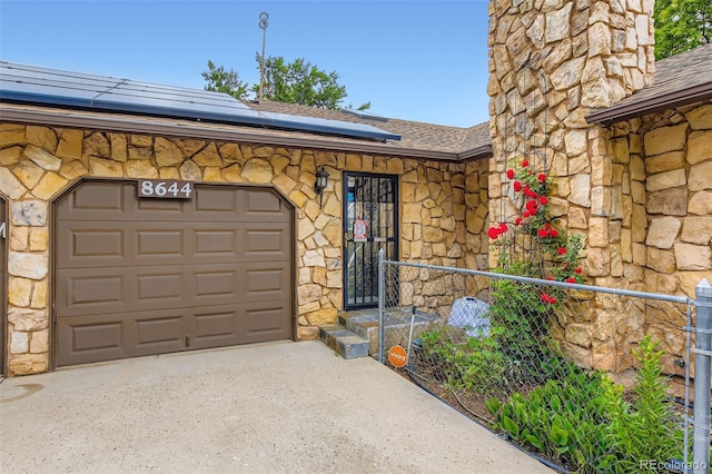 8644 S Brentwood St, Littleton, CO 80128 - view of exterior entry featuring stone siding, solar panels, driveway, and a shingled roof
