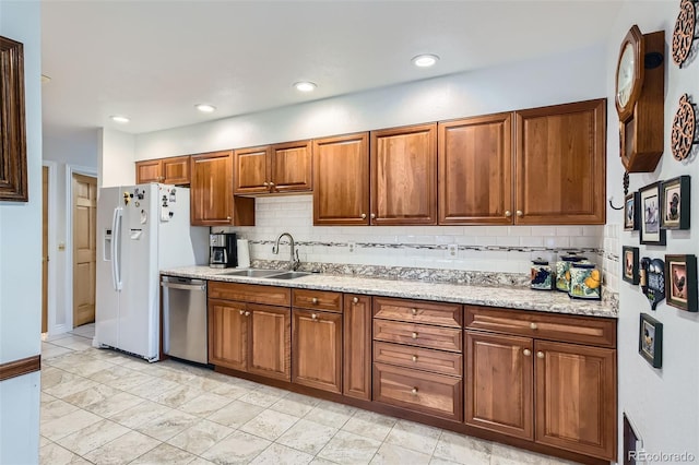 8644 S Brentwood St, Littleton, CO 80128 - kitchen with stainless steel dishwasher, white fridge with ice dispenser, brown cabinetry, decorative backsplash, and light stone counters