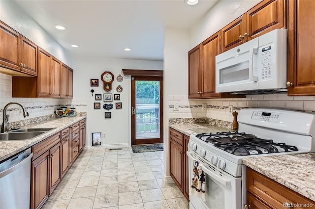 8644 S Brentwood St, Littleton, CO 80128 - kitchen with white appliances, backsplash, brown cabinets, and recessed lighting