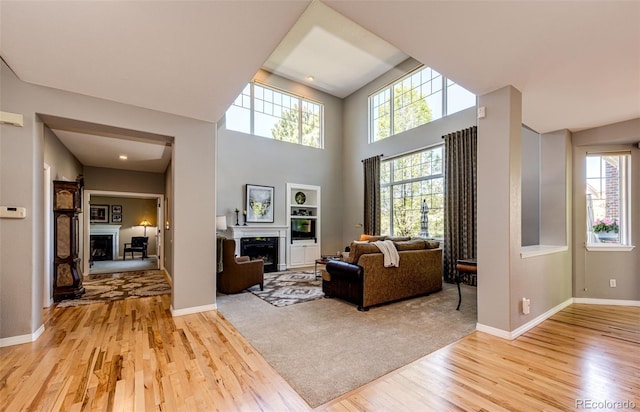 22685 E Calhoun Pl, Aurora, CO 80016 - living area featuring a fireplace, light wood-type flooring, baseboards, and a high ceiling